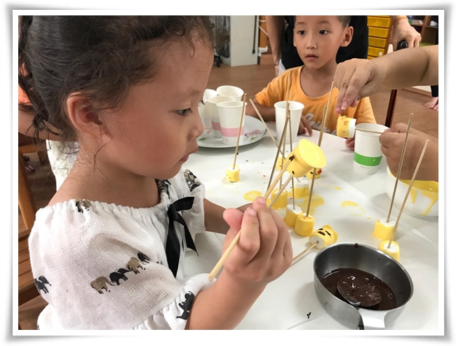 幼童專心地為棉花糖畫上表情