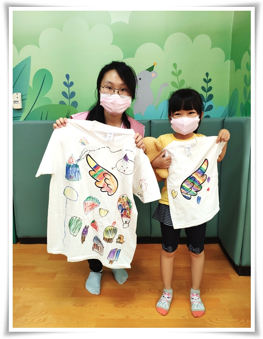 孩子為慢飛天使的翅膀塗上七彩的顏色，自信地展示出自己創作的手繪T-shirt的模樣十分可愛！