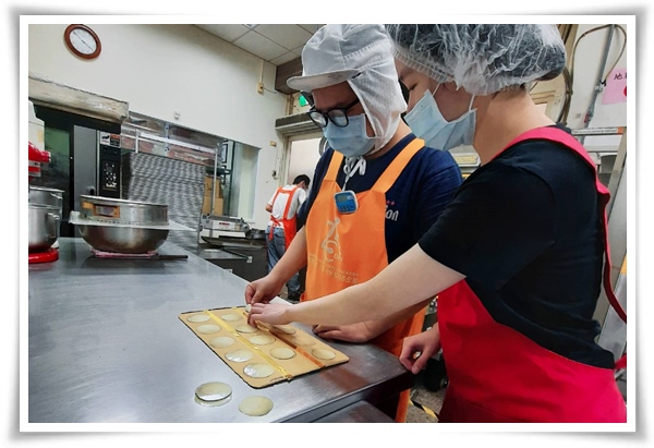 小揚(左)透過伊甸就業服務員的職務再設計，以輔具及圖示說明與練習烤餅乾時的排盤操作