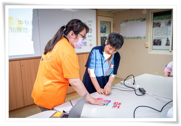 職能治療師楊沛璇(左)透過認知團體課程搭配自製圖卡，幫助智能障礙者反覆學習。
