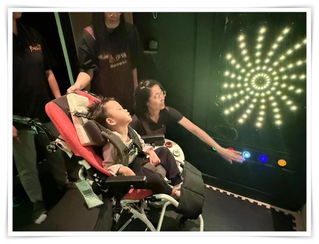 老師操作花火感官牆設備，樂樂的目光被閃爍躍動的燈光吸引，讓他的注意力能集中。