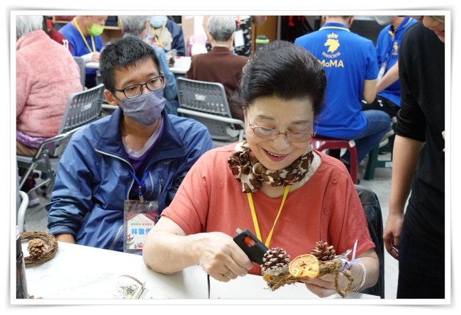 視力受限的王媽，仍專注地為手中的聖誕花圈細心點綴