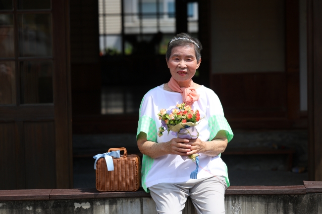李珠阿嬤拿著花與小籃子等道具，專業擺拍